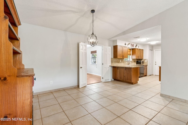 kitchen with a chandelier, light tile patterned flooring, brown cabinetry, a peninsula, and decorative backsplash