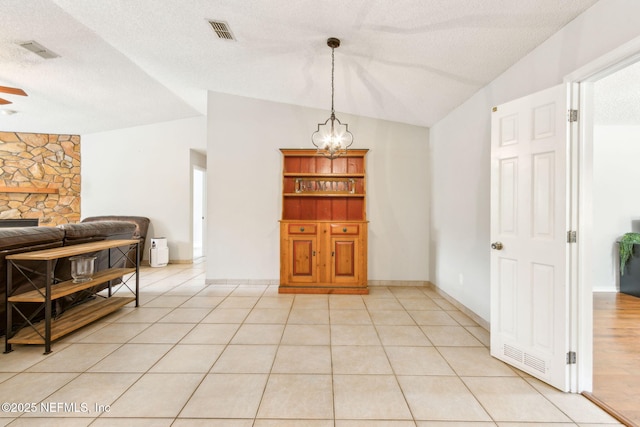 dining area featuring a chandelier, vaulted ceiling, a textured ceiling, ceiling fan, and light tile patterned floors