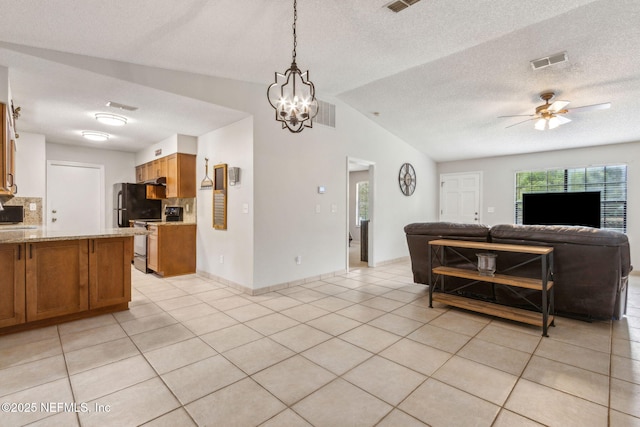 kitchen with open floor plan, range with electric stovetop, brown cabinets, light tile patterned flooring, and a textured ceiling
