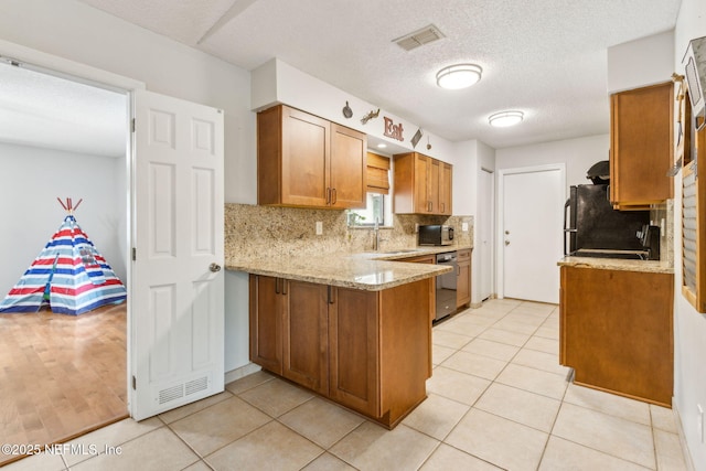 kitchen featuring a peninsula, brown cabinets, tasteful backsplash, light stone countertops, and stainless steel microwave