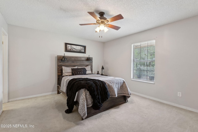 carpeted bedroom featuring a textured ceiling, baseboards, and ceiling fan