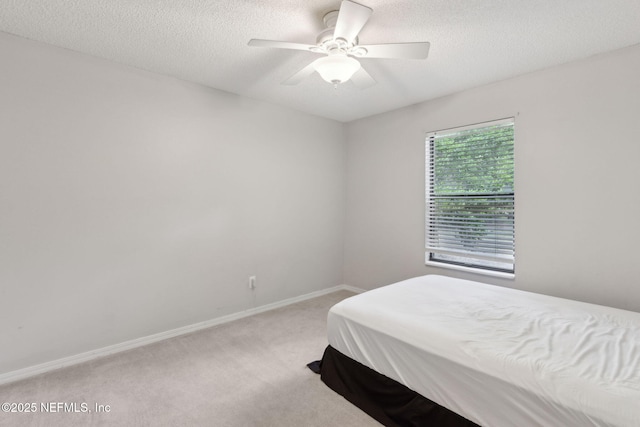 bedroom with light carpet, baseboards, a textured ceiling, and ceiling fan