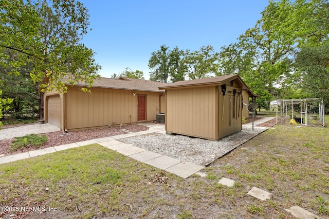 view of front of property featuring a garage, central AC unit, a shingled roof, an outdoor structure, and a storage shed