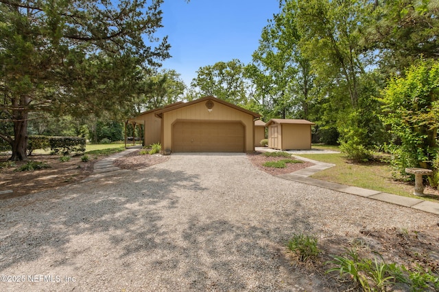 view of front of house featuring driveway, an outbuilding, an attached garage, and a storage unit