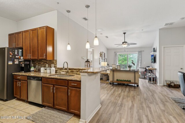 607 Golden Lake Loop, Saint Augustine, FL 32084 - kitchen featuring a sink, appliances with stainless steel finishes, vaulted ceiling, light wood-type flooring, and light stone countertops