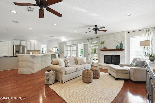living area with a ceiling fan, dark wood-style floors, recessed lighting, a fireplace, and a textured ceiling
