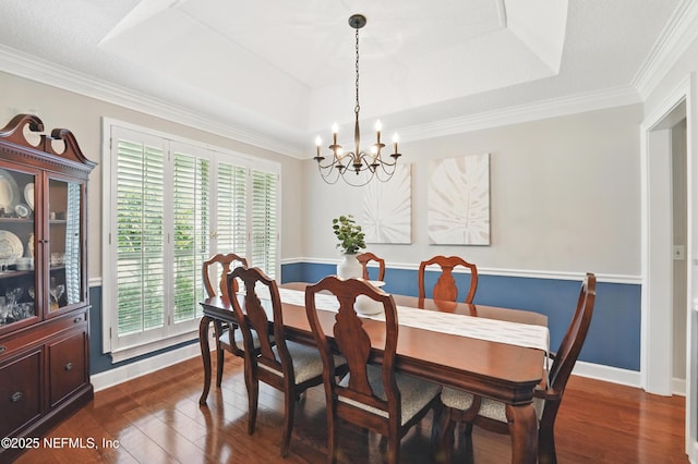dining space with a tray ceiling, a chandelier, dark wood-style flooring, baseboards, and crown molding