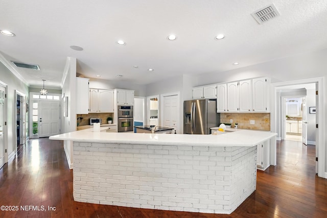 kitchen with appliances with stainless steel finishes, backsplash, white cabinets, dark wood-style flooring, and recessed lighting