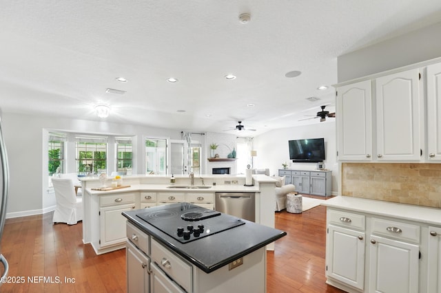 kitchen featuring a center island, stainless steel dishwasher, a sink, black electric cooktop, and ceiling fan