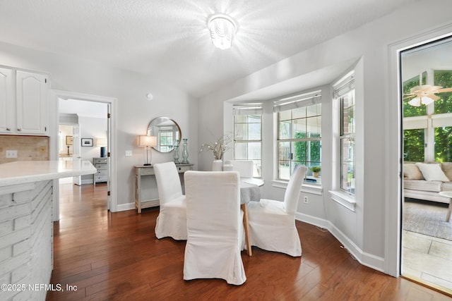 dining area with lofted ceiling, dark wood-style flooring, and baseboards