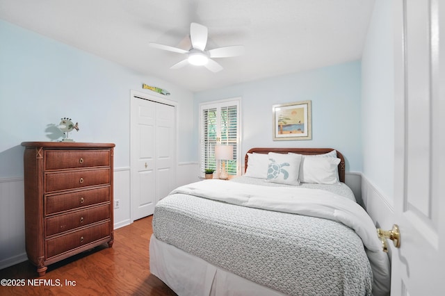 bedroom featuring wood finished floors, a closet, wainscoting, and a ceiling fan