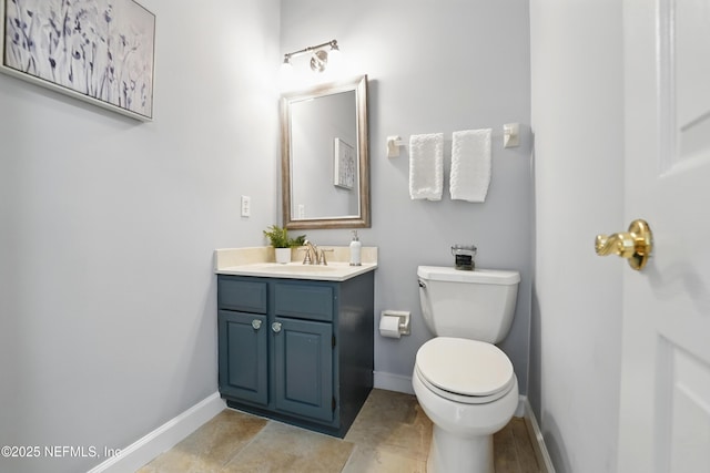 half bathroom with baseboards, toilet, and vanity