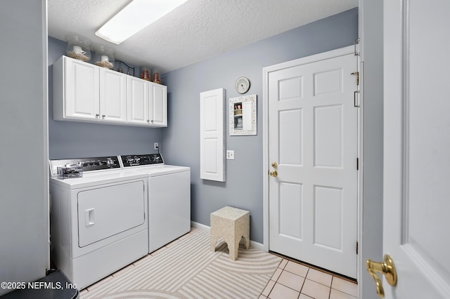 laundry room featuring washer and dryer, cabinet space, a textured ceiling, and light tile patterned floors