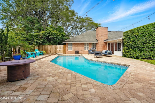 view of swimming pool featuring a patio area, an outdoor living space with a fire pit, and fence