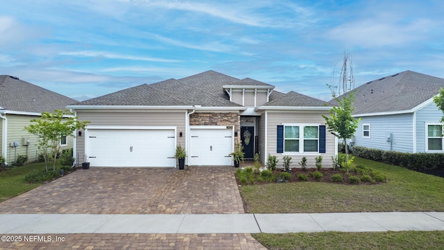 view of front facade featuring decorative driveway, a garage, a front yard, and roof with shingles