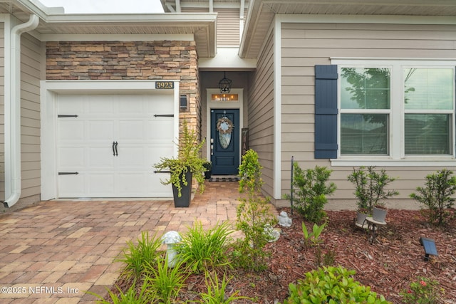 doorway to property with a garage and stone siding