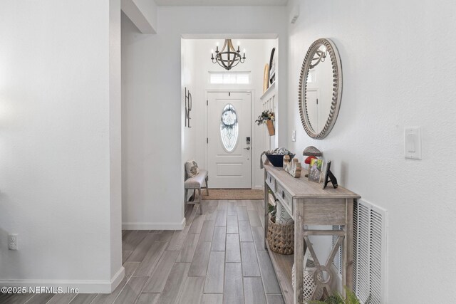 foyer featuring a chandelier, light wood-style flooring, and baseboards