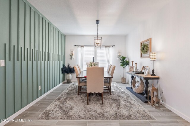 dining room featuring a chandelier, wood tiled floors, and baseboards