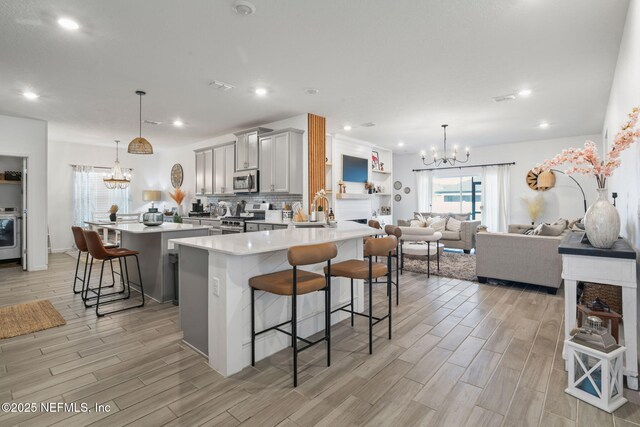 kitchen featuring a chandelier, stainless steel appliances, gray cabinets, a breakfast bar, and recessed lighting