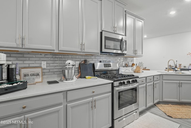 kitchen with stainless steel appliances, a sink, decorative backsplash, recessed lighting, and light stone counters