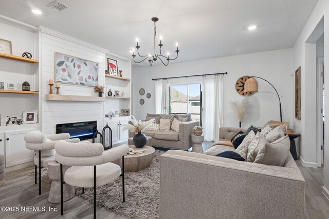 living area with wood finished floors, a chandelier, a large fireplace, recessed lighting, and built in features