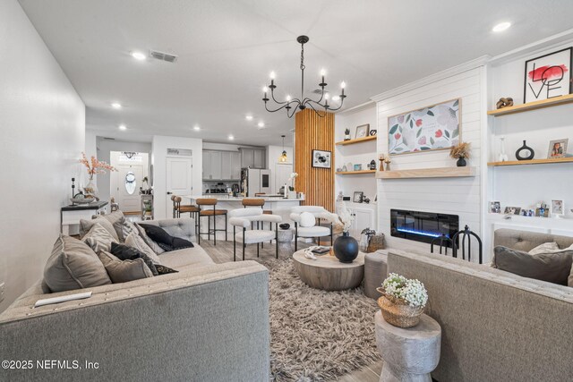 living area with light wood-style floors, recessed lighting, a fireplace, a chandelier, and built in shelves