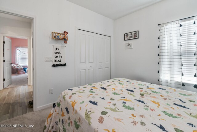 bedroom with a closet, light colored carpet, and baseboards