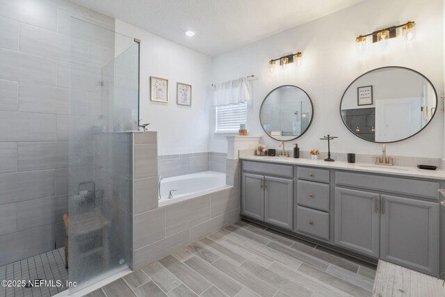 full bath featuring a garden tub, a walk in shower, double vanity, and recessed lighting