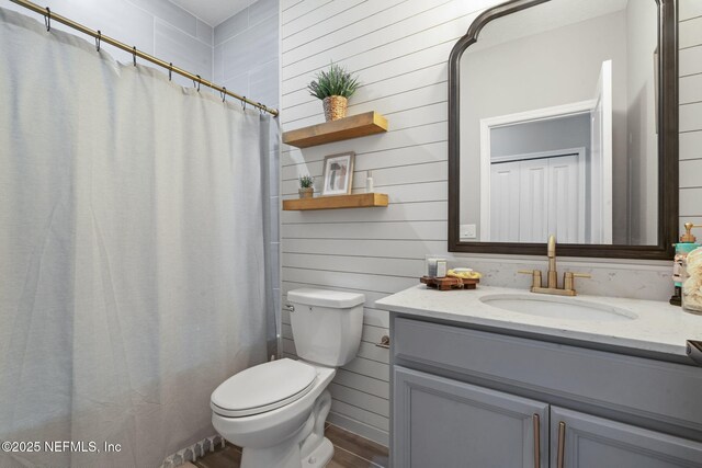 full bathroom featuring wood finished floors, vanity, toilet, wooden walls, and a shower with shower curtain