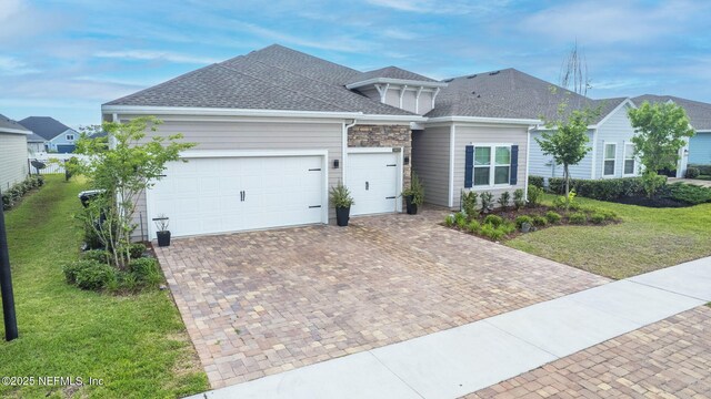 view of front of property with a garage, decorative driveway, a front yard, and a shingled roof