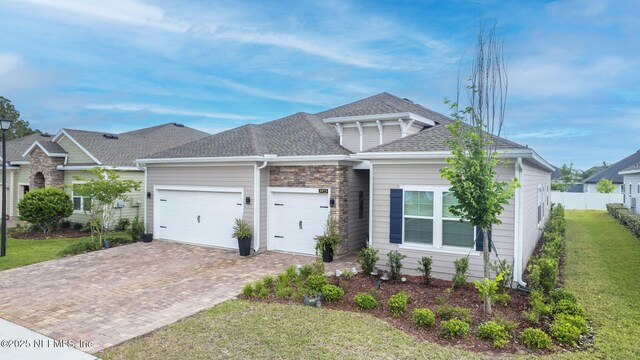 view of front of house featuring an attached garage, decorative driveway, and a shingled roof