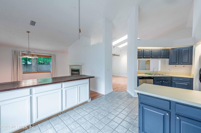 4837 Wethersfield Pl W, Jacksonville, FL 32257 - kitchen with vaulted ceiling, a sink, blue cabinets, a tiled fireplace, and light tile patterned flooring