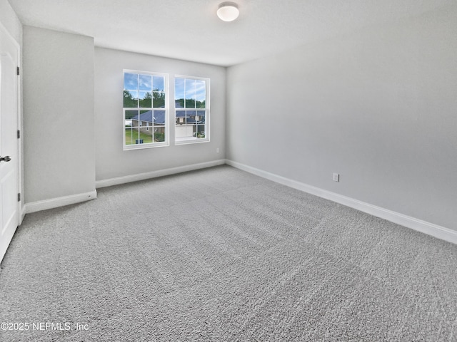 unfurnished room with carpet flooring and baseboards