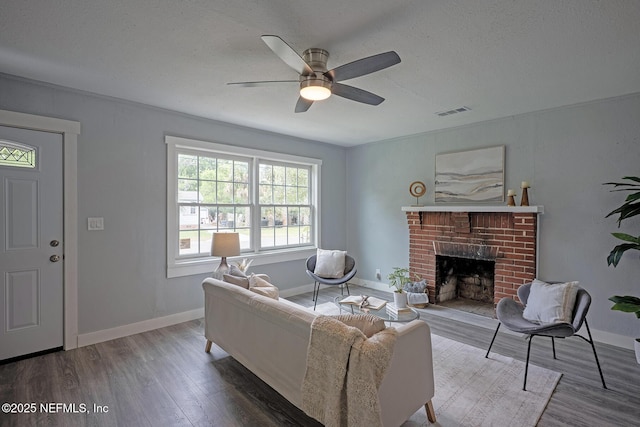 304 Lawton Ave, Jacksonville, FL 32208 - living room featuring wood finished floors, a ceiling fan, a brick fireplace, baseboards, and a textured ceiling