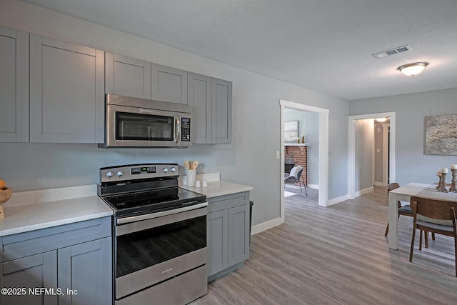 304 Lawton Ave, Jacksonville, FL 32208 - kitchen featuring appliances with stainless steel finishes, gray cabinetry, light countertops, light wood finished floors, and baseboards