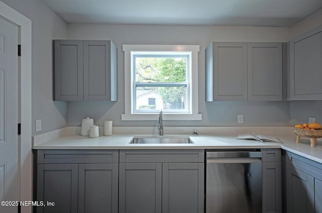304 Lawton Ave, Jacksonville, FL 32208 - kitchen with stainless steel dishwasher, gray cabinets, a sink, and light countertops