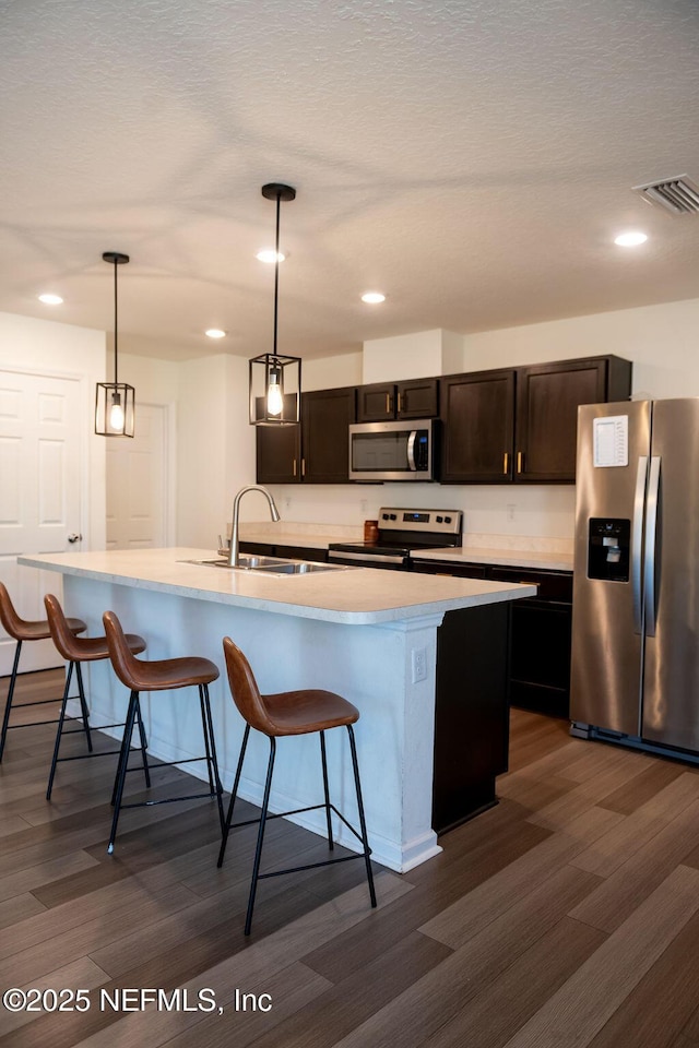 1863 Maxine Branch Way, Jacksonville, FL 32218 - kitchen featuring stainless steel appliances, a sink, a breakfast bar, dark wood-style floors, and light countertops