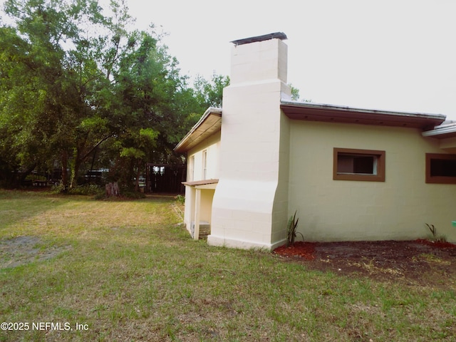 122 Husson Ave, Palatka, FL 32177 - view of home's exterior with concrete block siding, a chimney, and a yard