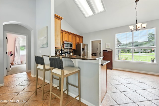 100 Bracken Ct, Saint Johns, FL 32259 - kitchen featuring stainless steel appliances, vaulted ceiling, arched walkways, a kitchen breakfast bar, and brown cabinets