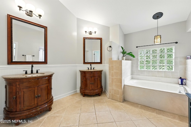 100 Bracken Ct, Saint Johns, FL 32259 - bathroom featuring a wainscoted wall, tile patterned floors, two vanities, a garden tub, and vaulted ceiling
