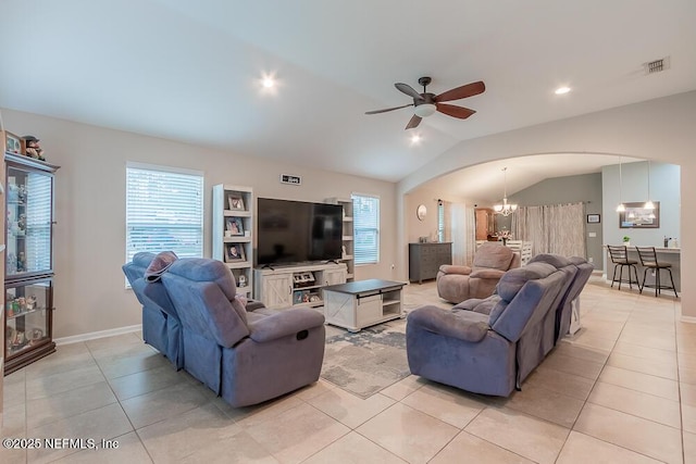 living area with arched walkways, a chandelier, vaulted ceiling, ceiling fan, and light tile patterned floors