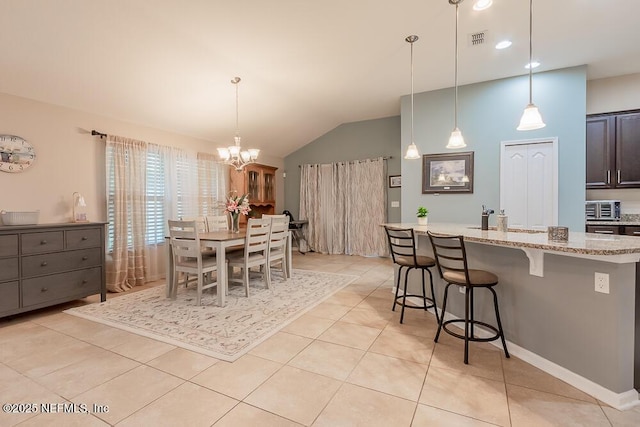 dining room featuring lofted ceiling, a chandelier, and light tile patterned flooring