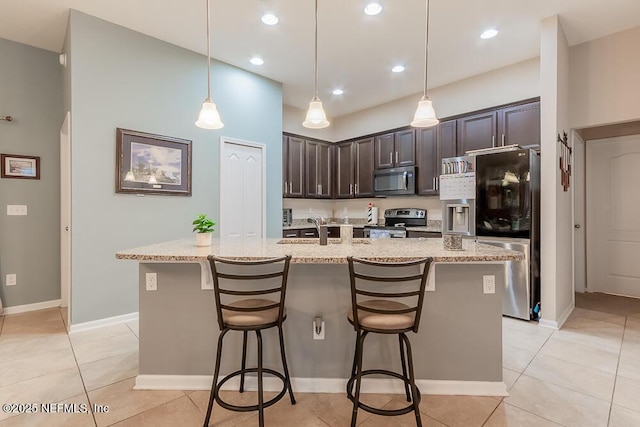 kitchen with appliances with stainless steel finishes, a breakfast bar area, dark brown cabinets, a sink, and recessed lighting