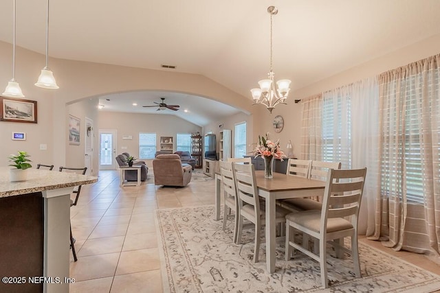 dining room featuring arched walkways, vaulted ceiling, light tile patterned flooring, a chandelier, and ceiling fan