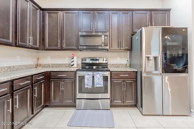 kitchen with appliances with stainless steel finishes, light tile patterned flooring, and dark brown cabinetry