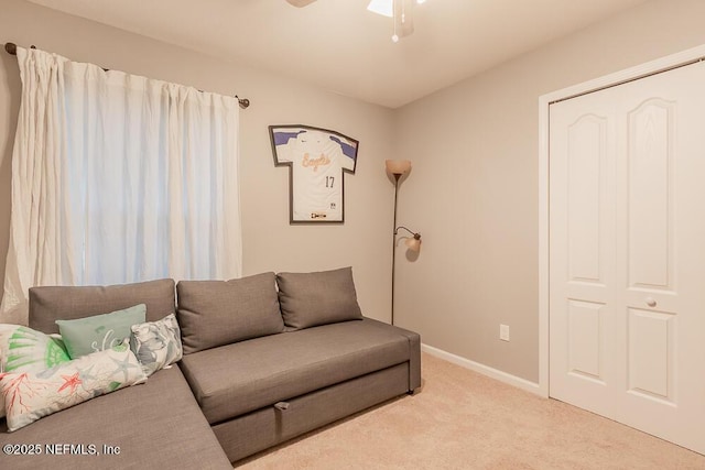 carpeted living area featuring baseboards and a ceiling fan