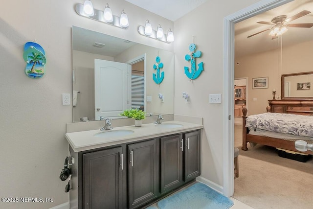 ensuite bathroom featuring a ceiling fan, double vanity, and baseboards