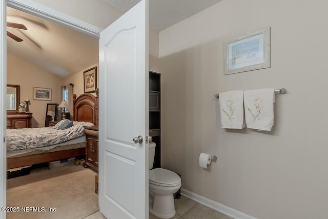 ensuite bathroom with ceiling fan, toilet, baseboards, and vaulted ceiling