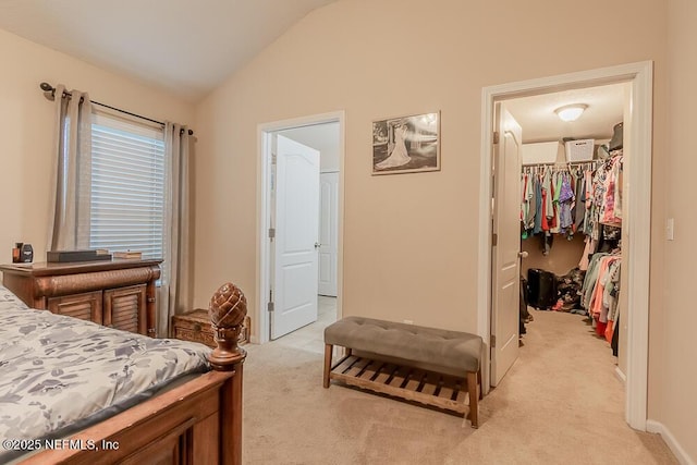 bedroom with a spacious closet, vaulted ceiling, light colored carpet, a closet, and baseboards