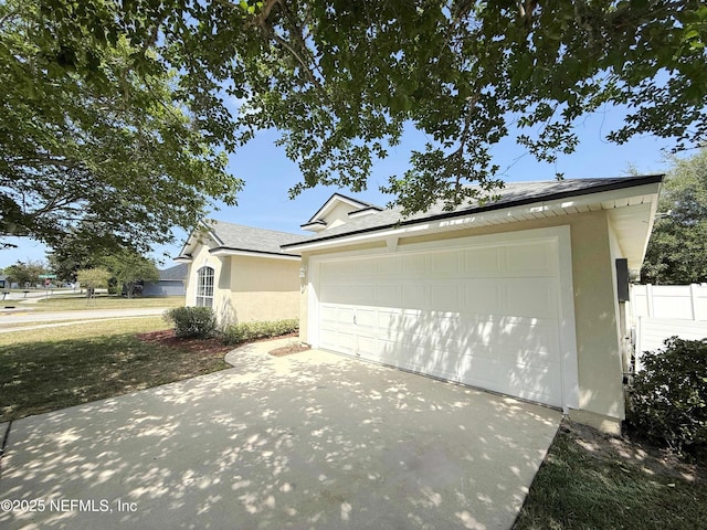 view of side of property featuring stucco siding, driveway, and roof with shingles